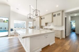 Agent and couple reviewing a luxury home listing with price comparisons on a kitchen counter.