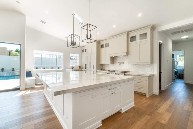 Agent and couple reviewing a luxury home listing with price comparisons on a kitchen counter.